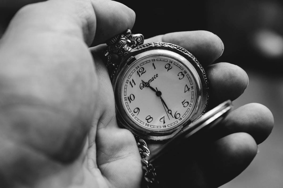 Een hand houdt een zakhorloge vast. Sfeerbeeld.
